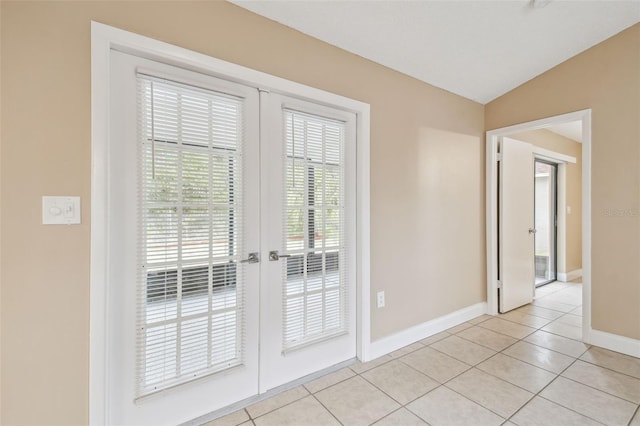 doorway with light tile patterned floors, vaulted ceiling, and french doors