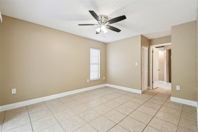 spare room with ceiling fan, light tile patterned floors, and a textured ceiling