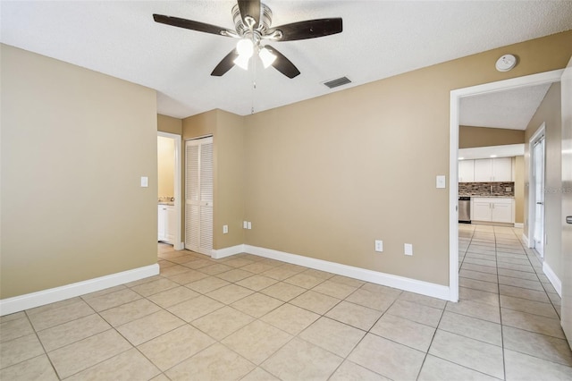 spare room featuring ceiling fan, a textured ceiling, and light tile patterned floors