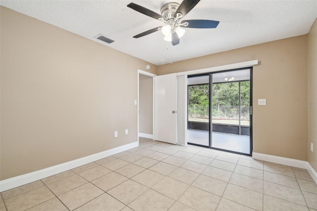 empty room with light tile patterned flooring, ceiling fan, and a textured ceiling