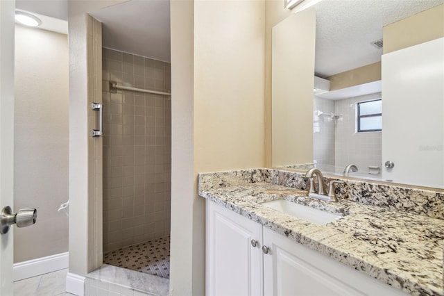 bathroom with vanity, tiled shower, and a textured ceiling