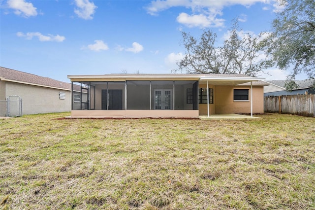 back of property featuring a lawn, a sunroom, and a patio area