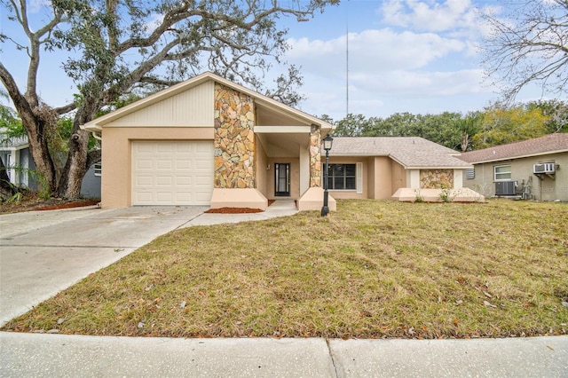 single story home featuring a garage, a front yard, a wall unit AC, and central air condition unit