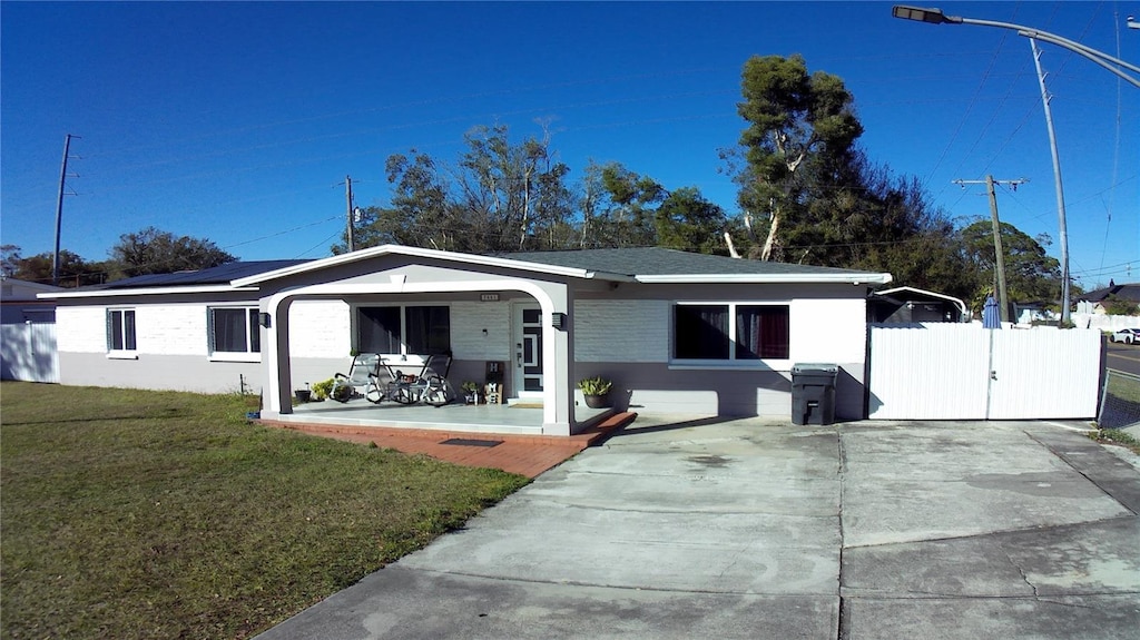 single story home with a porch, solar panels, and a front lawn