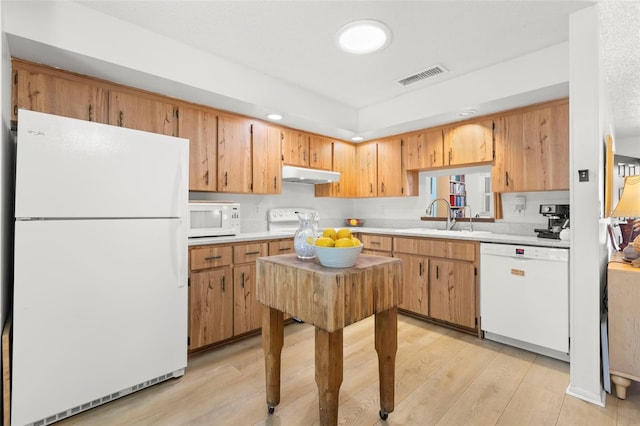 kitchen featuring white appliances, sink, light hardwood / wood-style flooring, and a textured ceiling