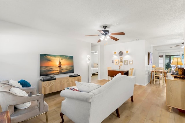 living room featuring a textured ceiling, light hardwood / wood-style floors, and ceiling fan