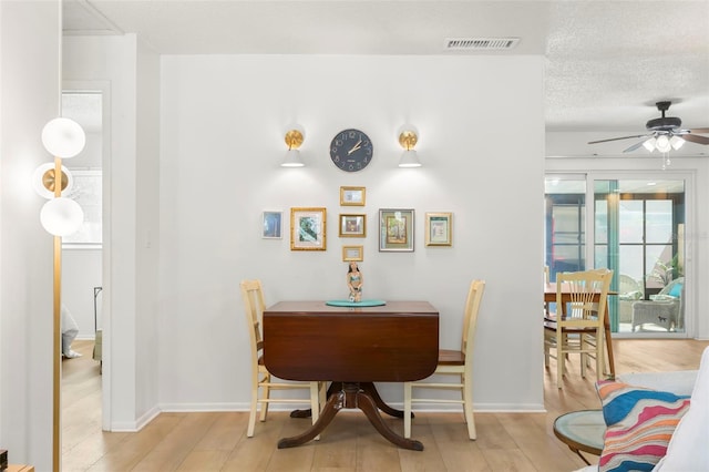 dining area featuring ceiling fan, a textured ceiling, and light hardwood / wood-style flooring