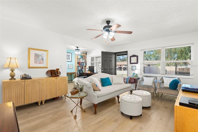 living room featuring ceiling fan, a textured ceiling, and light wood-type flooring