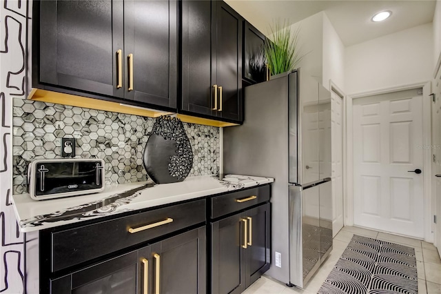 kitchen with stainless steel fridge, light tile patterned floors, and backsplash