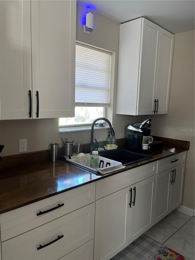 kitchen featuring light tile patterned flooring, sink, and white cabinets