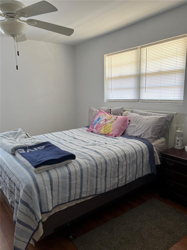 bedroom featuring multiple windows, dark hardwood / wood-style floors, and ceiling fan