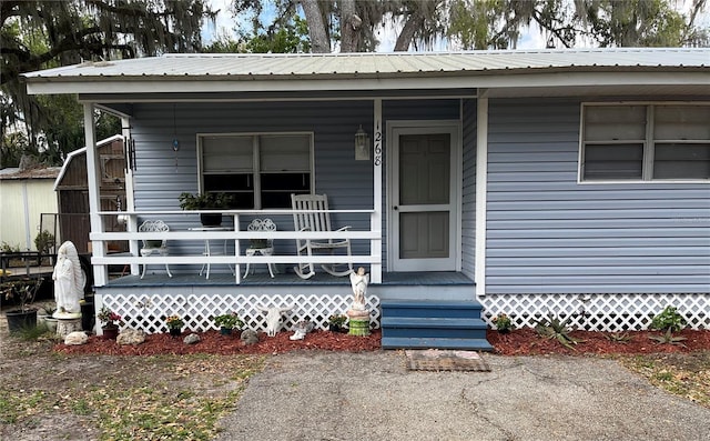 entrance to property featuring a porch and metal roof