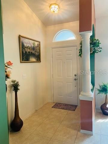 foyer entrance featuring decorative columns and light tile patterned floors