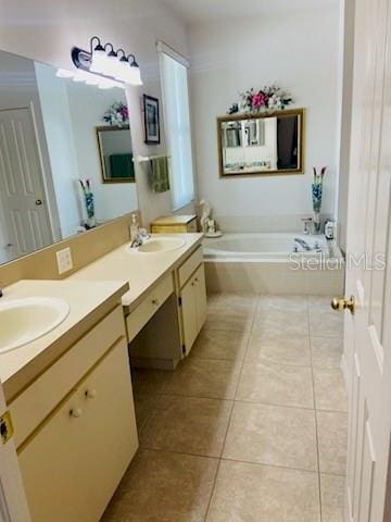 bathroom with a relaxing tiled tub, vanity, and tile patterned flooring