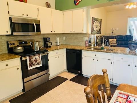 kitchen featuring white cabinetry, backsplash, dark stone countertops, and appliances with stainless steel finishes