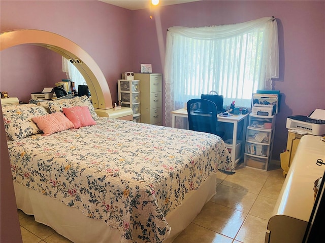 bedroom featuring arched walkways and light tile patterned flooring