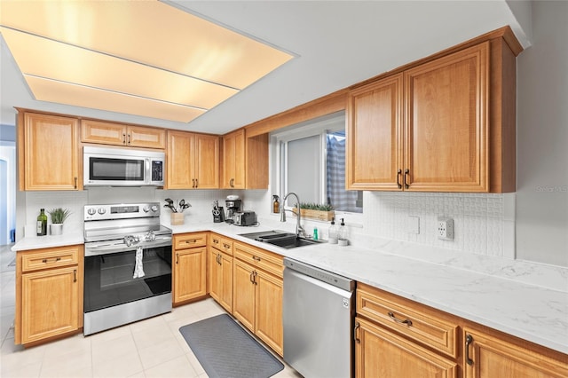 kitchen featuring sink, light tile patterned floors, stainless steel appliances, tasteful backsplash, and light stone counters