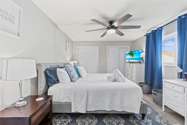 bedroom featuring hardwood / wood-style flooring, two closets, and ceiling fan