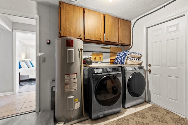 washroom featuring light tile patterned flooring, water heater, separate washer and dryer, cabinets, and a textured ceiling