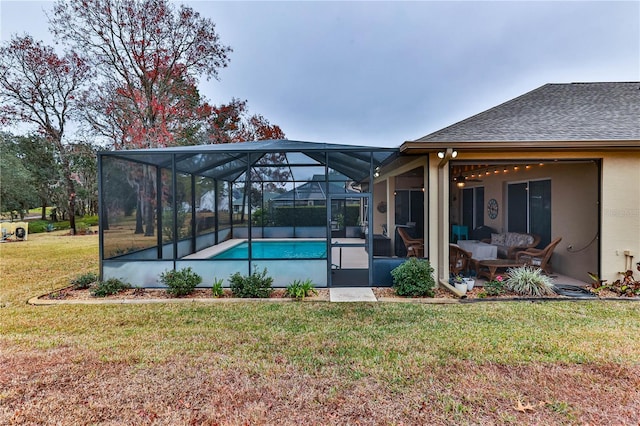 view of pool with a patio area, glass enclosure, and a lawn