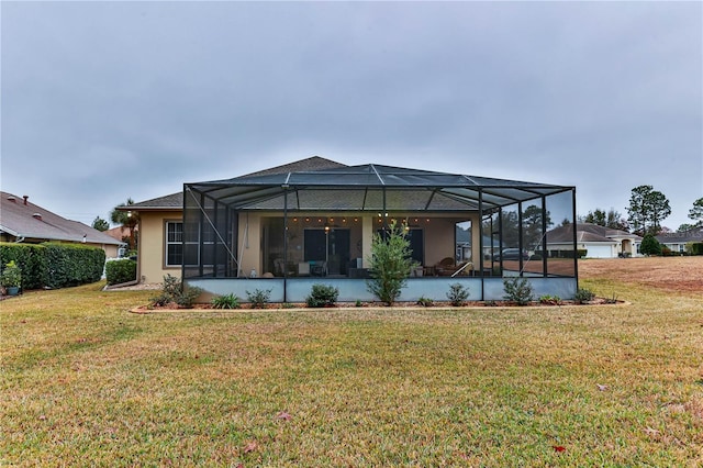 rear view of property with glass enclosure and a lawn