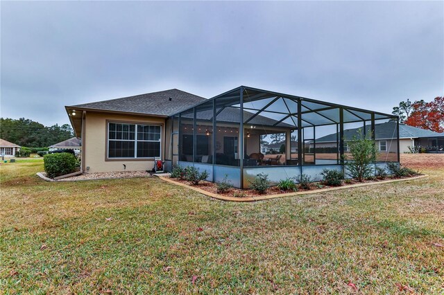 rear view of property featuring a yard and glass enclosure