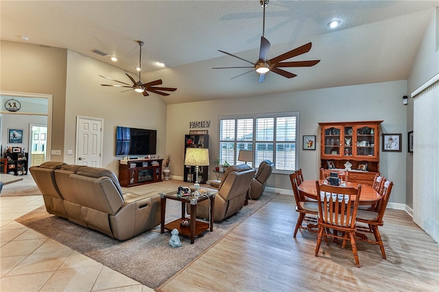 living room with ceiling fan, vaulted ceiling, and a textured ceiling