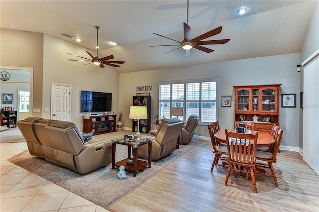 tiled living room with ceiling fan, lofted ceiling, and a textured ceiling