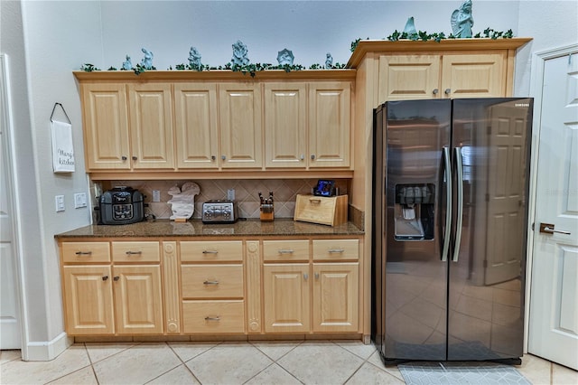 kitchen with stainless steel refrigerator with ice dispenser, light tile patterned flooring, and backsplash