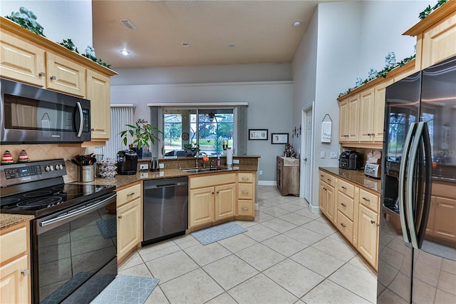 kitchen with sink, light tile patterned floors, light brown cabinets, and black appliances