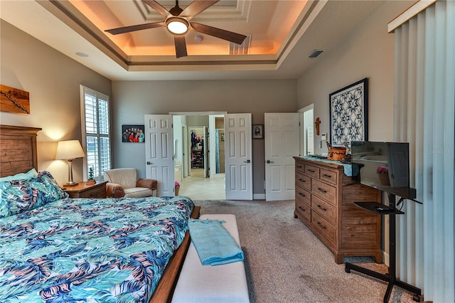 carpeted bedroom featuring a raised ceiling and ceiling fan