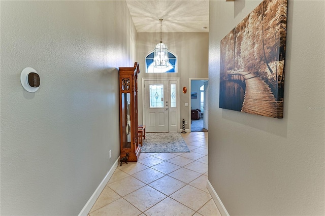 interior space featuring light tile patterned flooring, a towering ceiling, and a notable chandelier