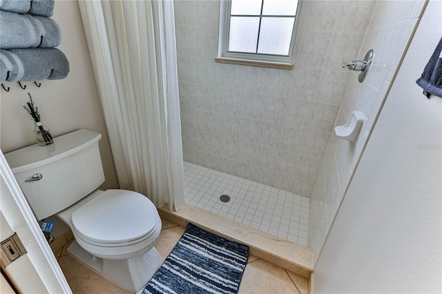 bathroom with a tile shower, tile patterned floors, and toilet