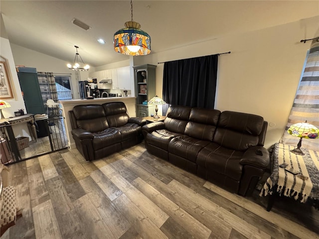 living room featuring hardwood / wood-style flooring, vaulted ceiling, and an inviting chandelier