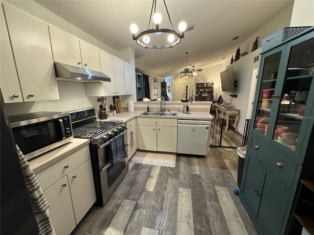 kitchen with lofted ceiling, sink, appliances with stainless steel finishes, hanging light fixtures, and white cabinets