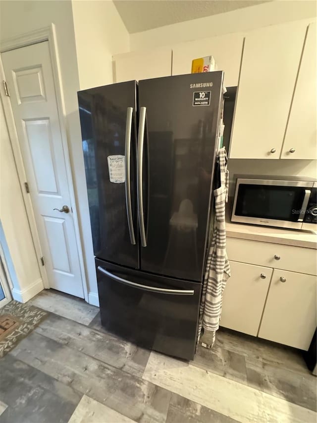 interior details featuring white cabinets and refrigerator