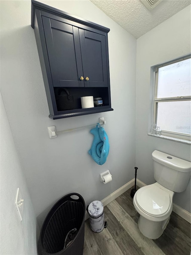 bathroom with wood-type flooring, toilet, and a textured ceiling