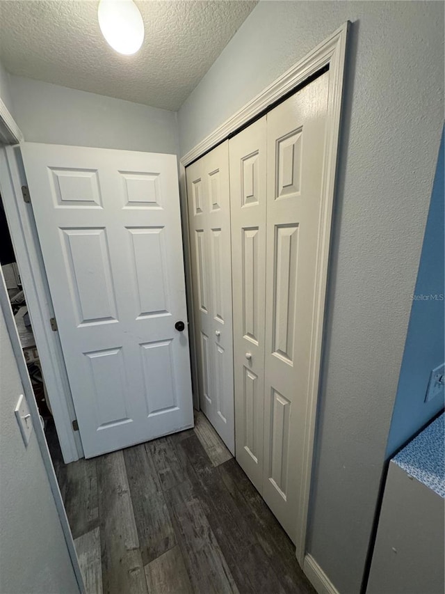 hallway with dark wood-type flooring and a textured ceiling