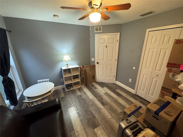 misc room featuring ceiling fan, dark wood-type flooring, and a textured ceiling