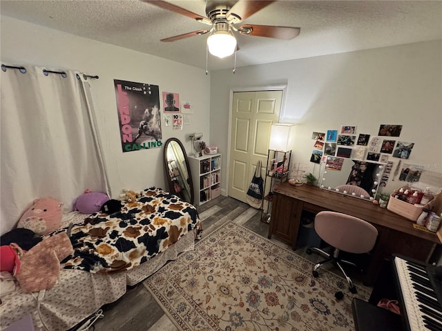 bedroom featuring hardwood / wood-style flooring, ceiling fan, a closet, and a textured ceiling