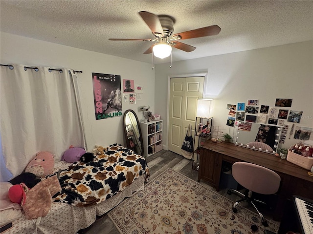 bedroom with wood-type flooring, a textured ceiling, ceiling fan, and a closet