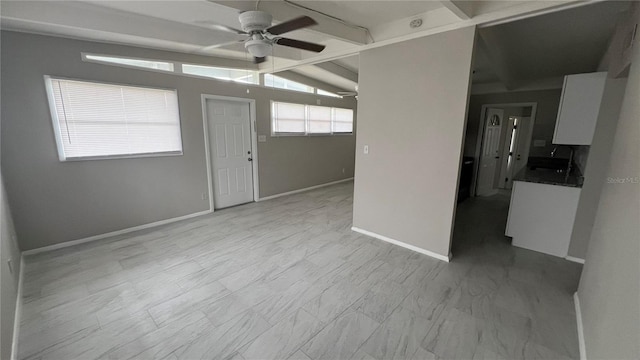 empty room with ceiling fan, sink, and lofted ceiling with beams