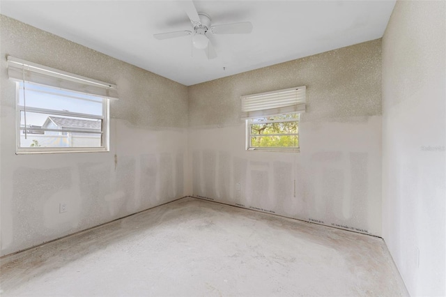 unfurnished room with ceiling fan and concrete floors