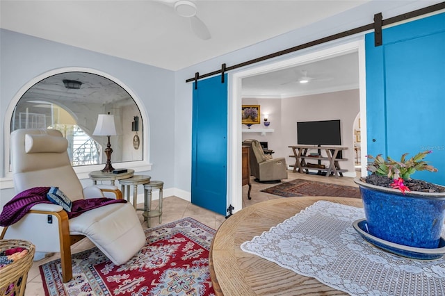 interior space featuring a barn door, baseboards, a ceiling fan, ornamental molding, and light tile patterned flooring