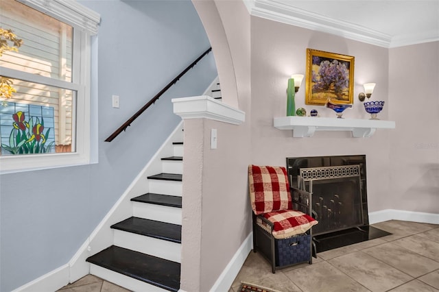 stairway featuring a fireplace with flush hearth, tile patterned flooring, crown molding, and baseboards