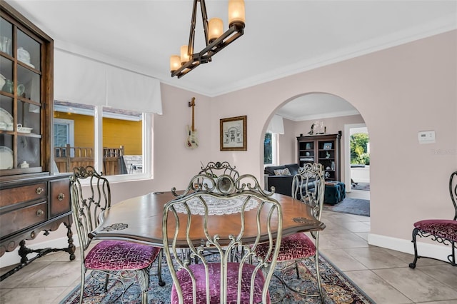 dining area featuring baseboards, arched walkways, ornamental molding, a notable chandelier, and light tile patterned flooring