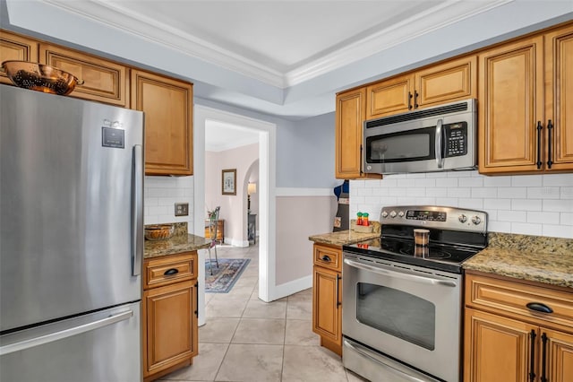 kitchen featuring arched walkways, stainless steel appliances, light stone counters, and ornamental molding