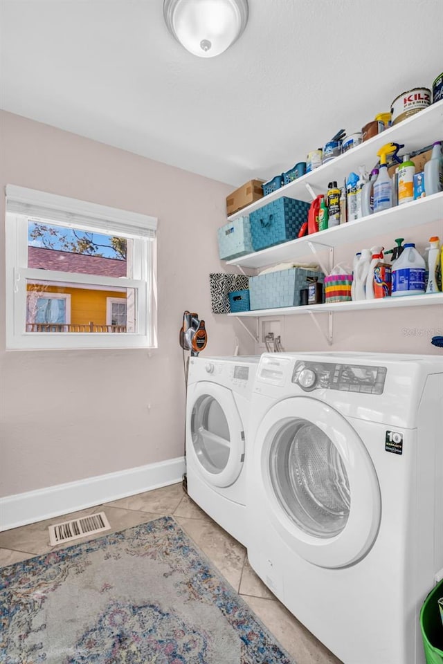 clothes washing area with light tile patterned floors and washer and clothes dryer