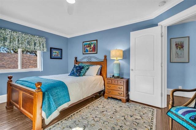 bedroom featuring baseboards, wood finished floors, and crown molding