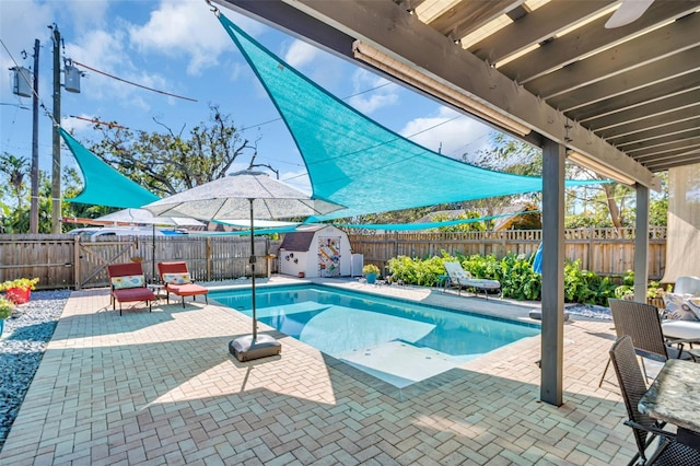 view of swimming pool featuring an outbuilding, a patio, a fenced backyard, a storage shed, and a fenced in pool